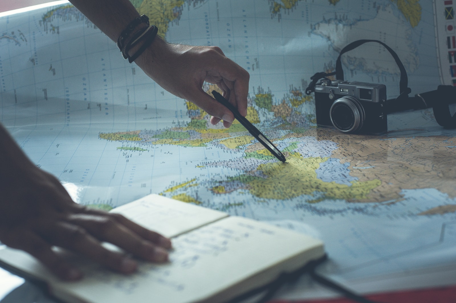 Métiers de l'international formation continue expat Personne cherchant une destination sur un planisphère avec dans ses mains un stylo et un cahier