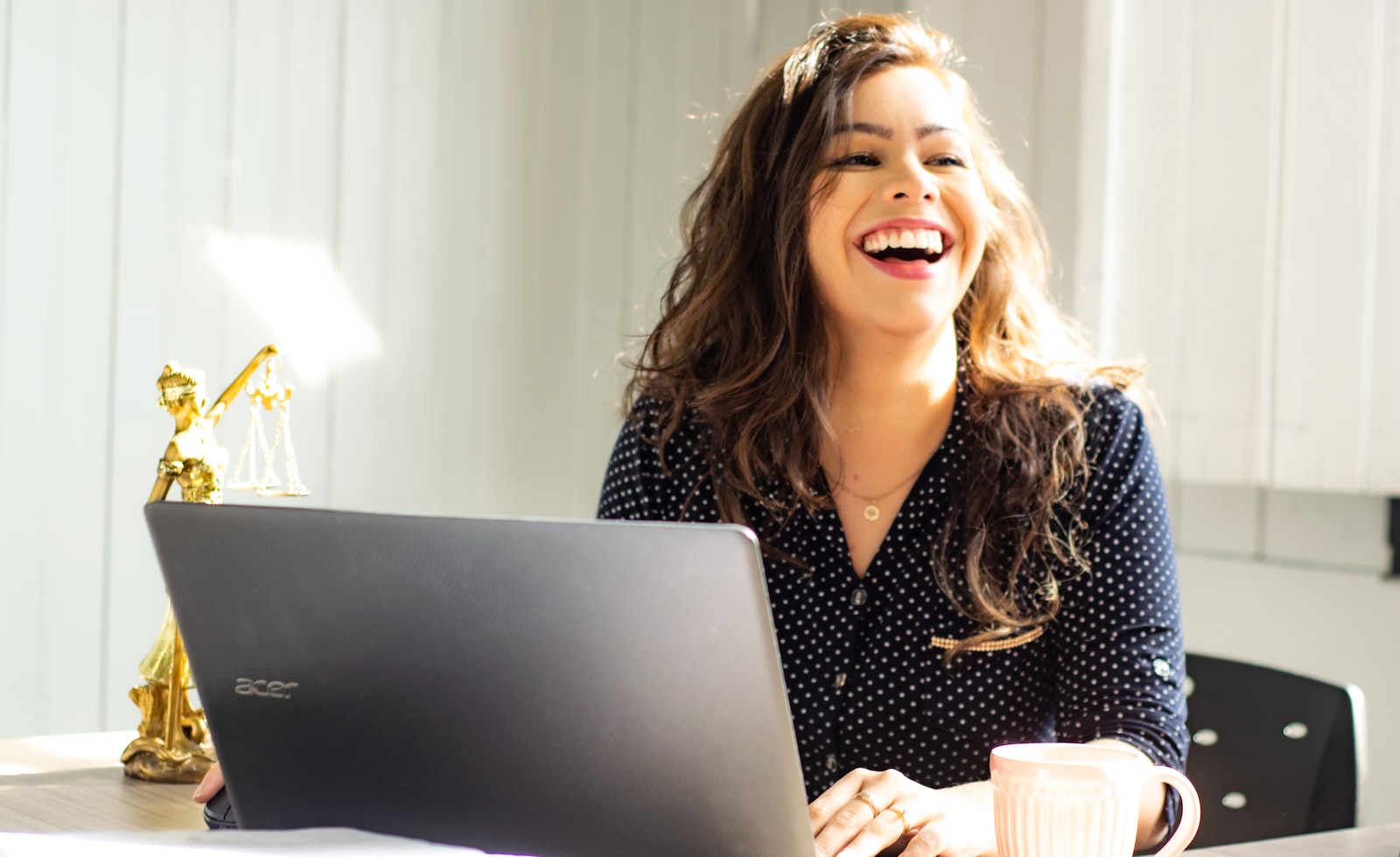 femme travaillant devant son ordinateur portable assise à son bureau en souriant